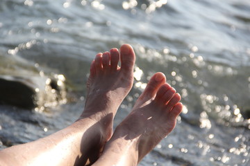 Fototapeta na wymiar Two women's feet on a shingle beach by the sea