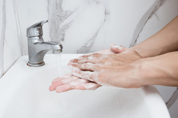 Young man washing hands over sink in bathroom, closeup, Corona virus or Covid-19 prevention,...