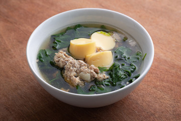 Boiled minced pork and tofu soup with gourd in white bowl on wooden table, Thai food, Healthy food.