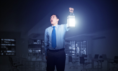 Scared businessman holding glowing lantern