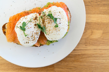 Healthy food. Sandwich with fish: coarse-grained bread, cream cheese, guacomolli cheese, salmon, poached egg, greens. Ready to eat.