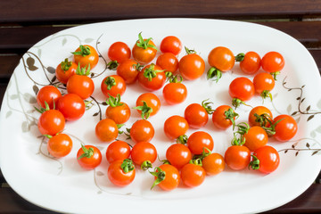 Red mini tomatoes on the white ceramic plate