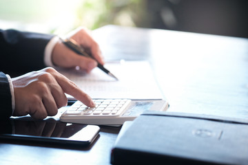 Businessman analyzing investment charts and pressing calculator buttons over documents. Accounting Concept.