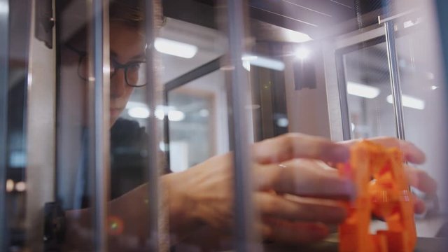 Male college student studying engineering using 3D printing machine - shot in slow motion
