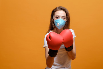 woman in boxing gloves, home quarantine, coronavirus pandemic, on yellow orange background, battle...