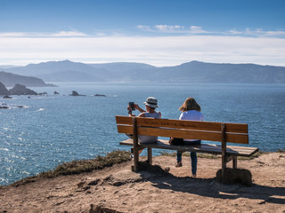 Two tourists on the best bench/"bank" of the world at Loiba, Ortigueira, Rias Altas, Galicia, Spain