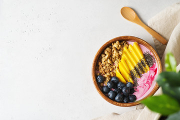 Asai bowl granola oatmeal with mango, blueberry and chia seeds in wooden plate on white background