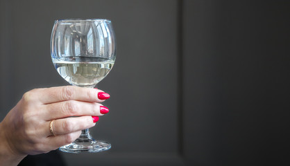 female hand holds a glass with white wine