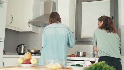 Two young pretty women fast busy cooking in the bright kitchen. Friends are cooking together.