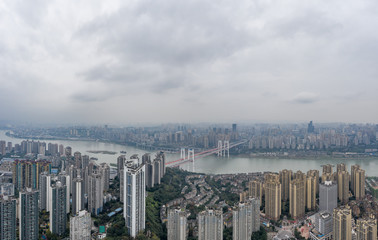 Aerial drone shot of Caiyuanba Bridge over Yangtze river and dense riverside residential building along in Chongqing, China