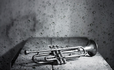 the ancient jazz trumpet behind the window with rain drops - obrazy, fototapety, plakaty