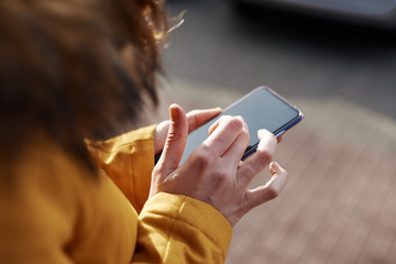 Woman using smartphone in the city outdoor, close up. Female hands typing message on mobile phone