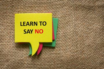 Top view stack of a colorful speech bubbles written with quotes Learn To Say No on a brown rugs...