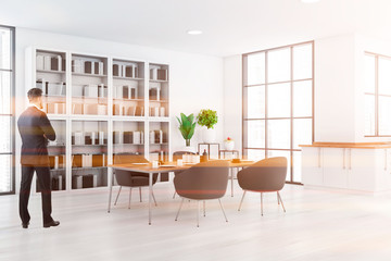 Man in white kitchen with table and bookcase
