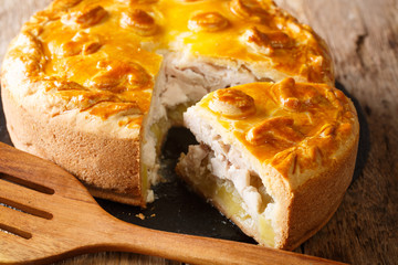 layered sliced pie Kurnik stuffed with chicken potatoes and onions close-up on a slate board. horizontal © FomaA