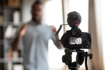 Close up focus on digital camera filming equipment, showing skilled smart mixed race man sharing knowledge, recording educational seminar, webinar, training, lecture or job grant interview indoors.