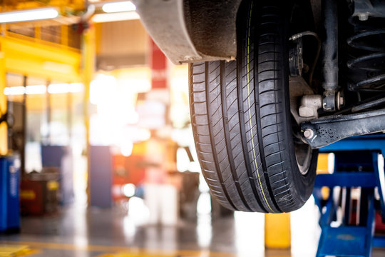 Car Automobile Mechanic Working On Repairing The Wheel Tire Of Vehicle, Taking Car In For Service Workshop For Male Car Mechanic Fixing Problems Replacing Broken Parts Of Using Tools And Equipment