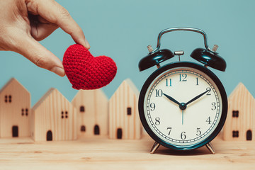 Love heart with time clock with wooden home background for times to stay at home concept.