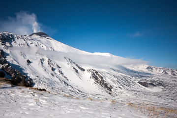 Fototapeta na wymiar Mount Etna with snow, The active volcano with smoke and ash is coming from the crater. Etna National Park, Sicily, Italy