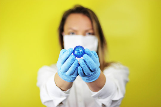 Image of young nurse or doctor woman wearing medical face mask and disposable gloves showing coronavirus isolated against yellow background