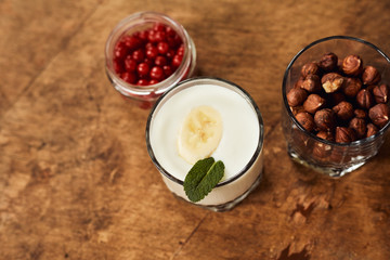 Yogurt with nuts on a wooden light background. View from above. Natural yogurt.
