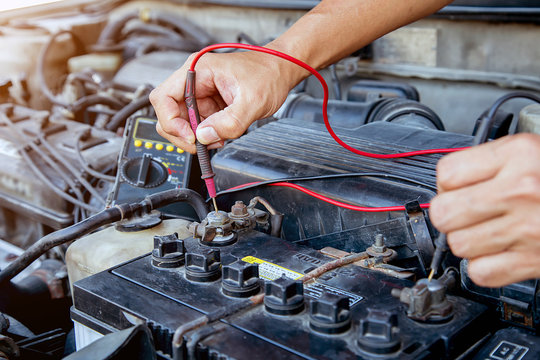 Technician using measuring equipment for checking car battery. Concepts of car Repair service and car insurance.