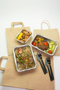 Lunch and dinner with home delivery in foil boxes and paper bag on a white background.
