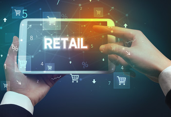 Close-up of a hand holding tablet with RETAIL inscription, online shopping concept