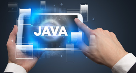 Close-up of a hand holding tablet with JAVA abbreviation, modern technology concept