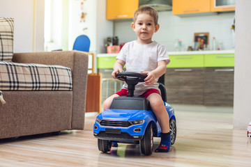 Happy little boy drive on a toy car in the flat. Activity for a child when stayed at home