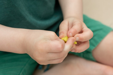 yellow piece of plasticine in the hands of a young child.