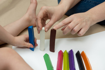 Fototapeta premium a little boy with his mother are building a multi-colored fence from plasticine bars. family leisure. close-up