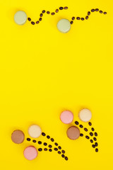 Cookies macaron of different colors on a yellow background, coffee beans. Copy space.