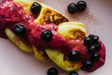 Cheesecakes with cherry jam and blueberries close-up on a plate. Pancakes with jam and blueberries.