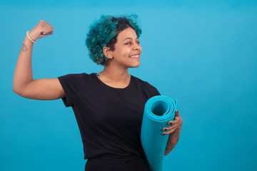 girl or woman with gym mat and raised arm isolated on color background