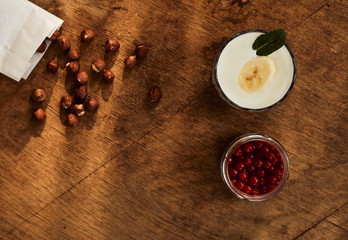 Yogurt with nuts on a wooden light background. Natural yogurt. View from above. Summer food.