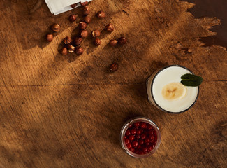 Yogurt with nuts on a wooden light background. Natural yogurt. View from above. Summer food. © aporubaymykh