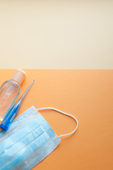 Protective face masks, thermometer and hand  sanitizing gel bottle on neutral background. Concept of coronavirus pandemic. Virus and COVID-19 self protection.