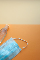 Protective face mask and hand  sanitizing gel bottle on neutral background. Concept of coronavirus pandemic. Virus and COVID-19 self protection.