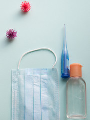 Protective face masks, thermometer and hand  sanitizing gel bottle on neutral background. Concept of coronavirus pandemic. Virus and COVID-19 self protection.