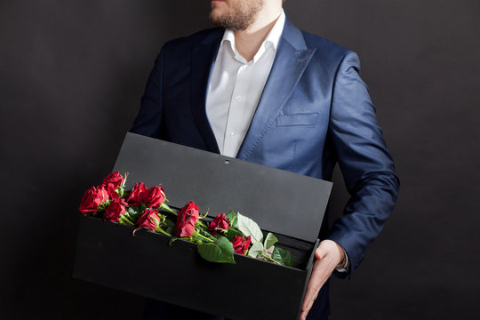 man gives red roses in an original box to his beloved woman