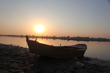 wooden boat at river shore with sunset. Old boat vintage look with sunset horizon in evening