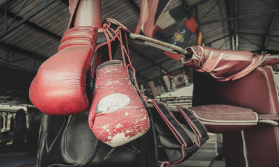 A pair of old Muay Thai boxing gloves hangs on the boxing ring at training  camp