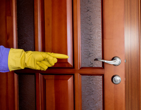 Hand In A Rubber Glove Points To The Door Handle. Disinfection During The Virus Epidemic. Cleaning The Apartment