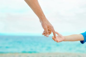 beautiful hands of a happy parent and child by the sea in nature