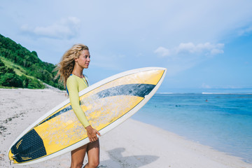 Young woman with surfboard looking at sea