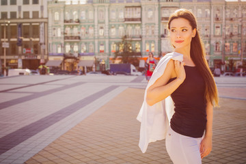 Beautiful brunette business woman in white suit and black t-shirt outdoors. copy space