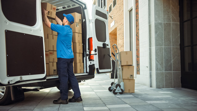 Delivery Man Uses Hand Truck Trolley Full of Cardboard Boxes and Packages, Loads Parcels into Truck / Van. Professional Courier / Loader helping you Move, Delivering Your Purchased Items Efficiently - Powered by Adobe