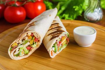 shawarma lavash wrap with chicken meat tomatoes lettuce cucumber sauce potato on cutting board 