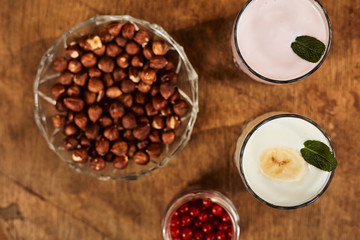 Yogurt with nuts on a wooden background. View from above. Summer food.